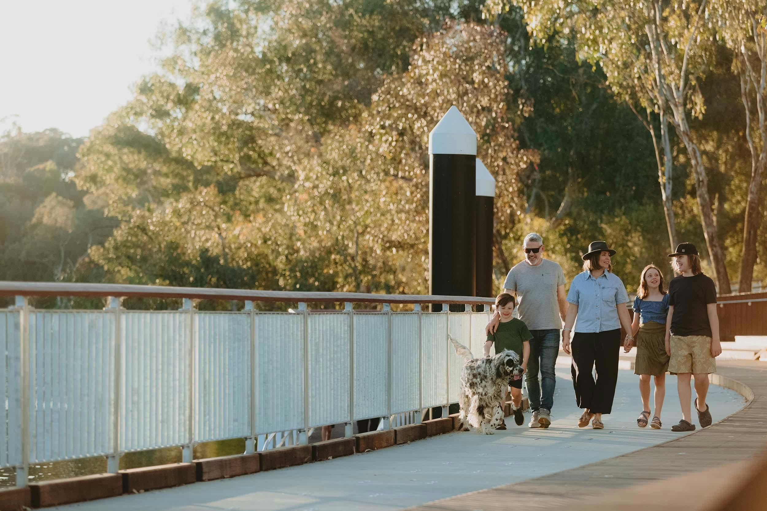 Family of five walking their dog along the boardwalk.