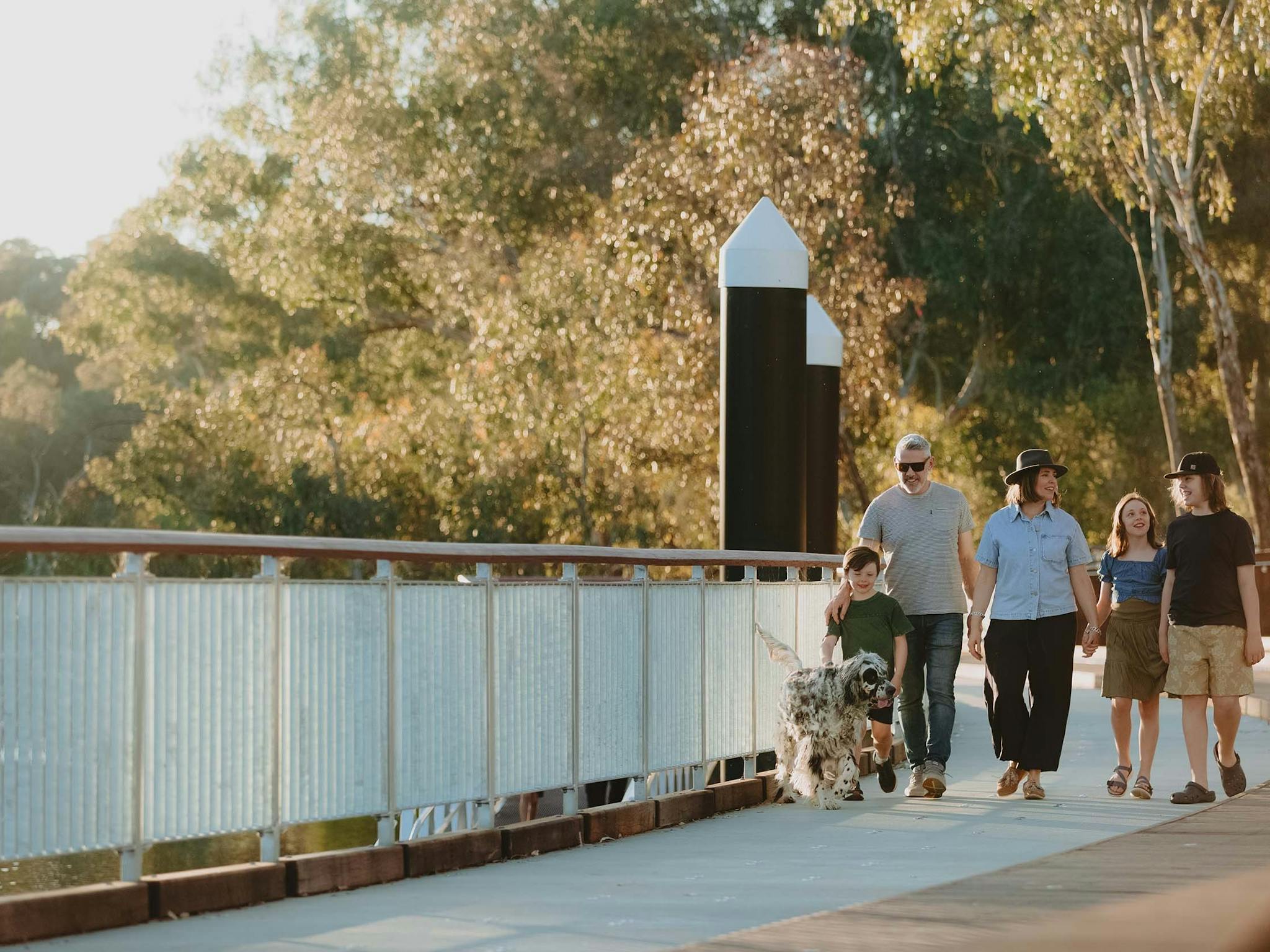 Family of five walking their dog along the boardwalk.