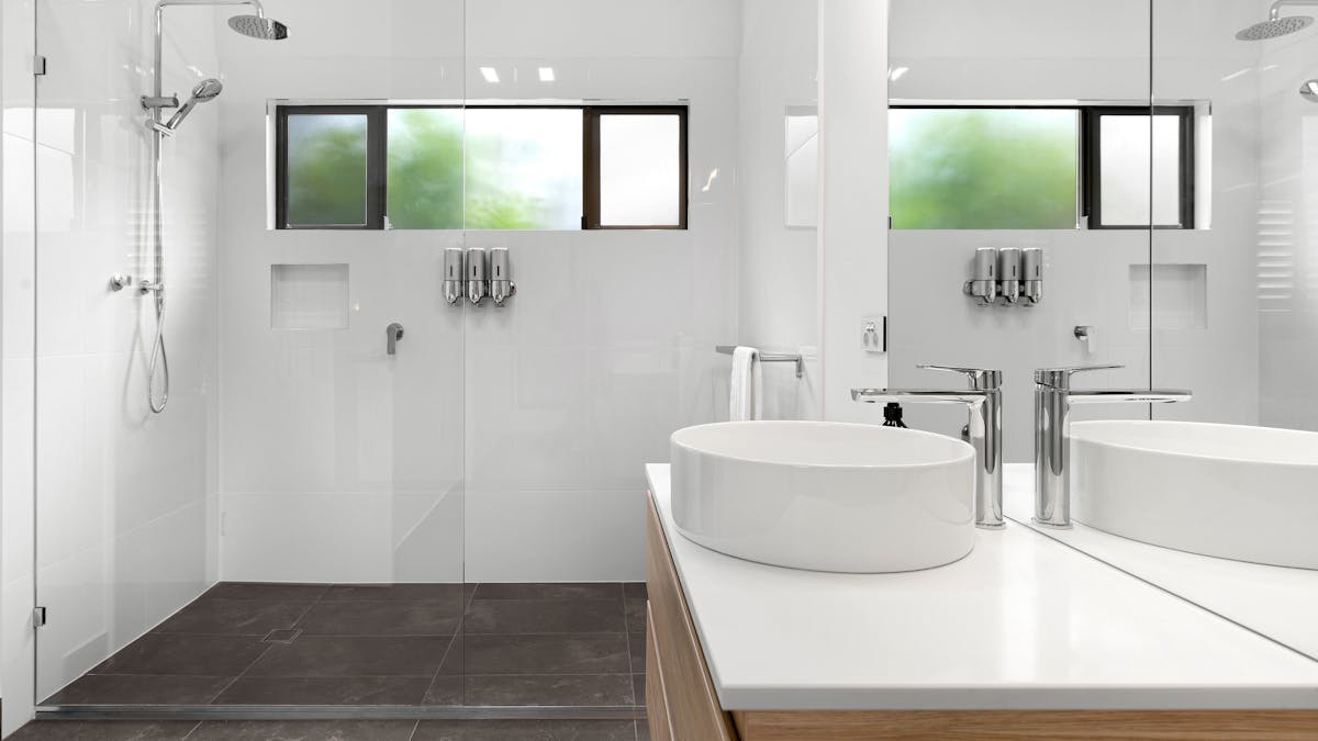 Image of large open modern shower with white basin in foreground on top of bathroom cabinetand