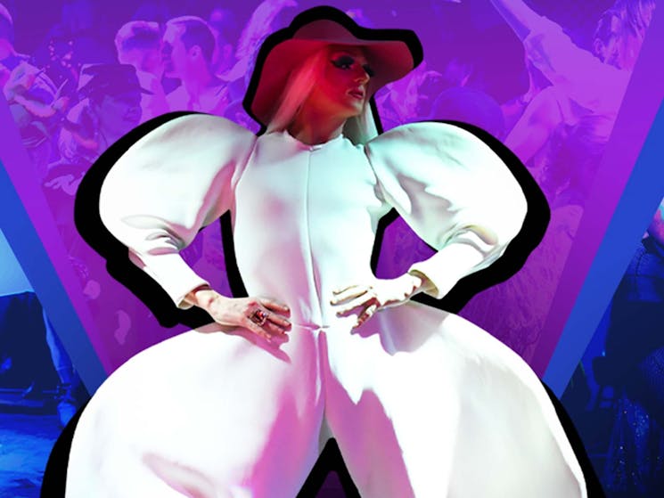 Drag Queen with their hands on their hips in a structured white pantsuit