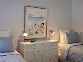 Bright bedroom with blue linen bedding, framed artwork and soft natural light at Harolds on the Hill