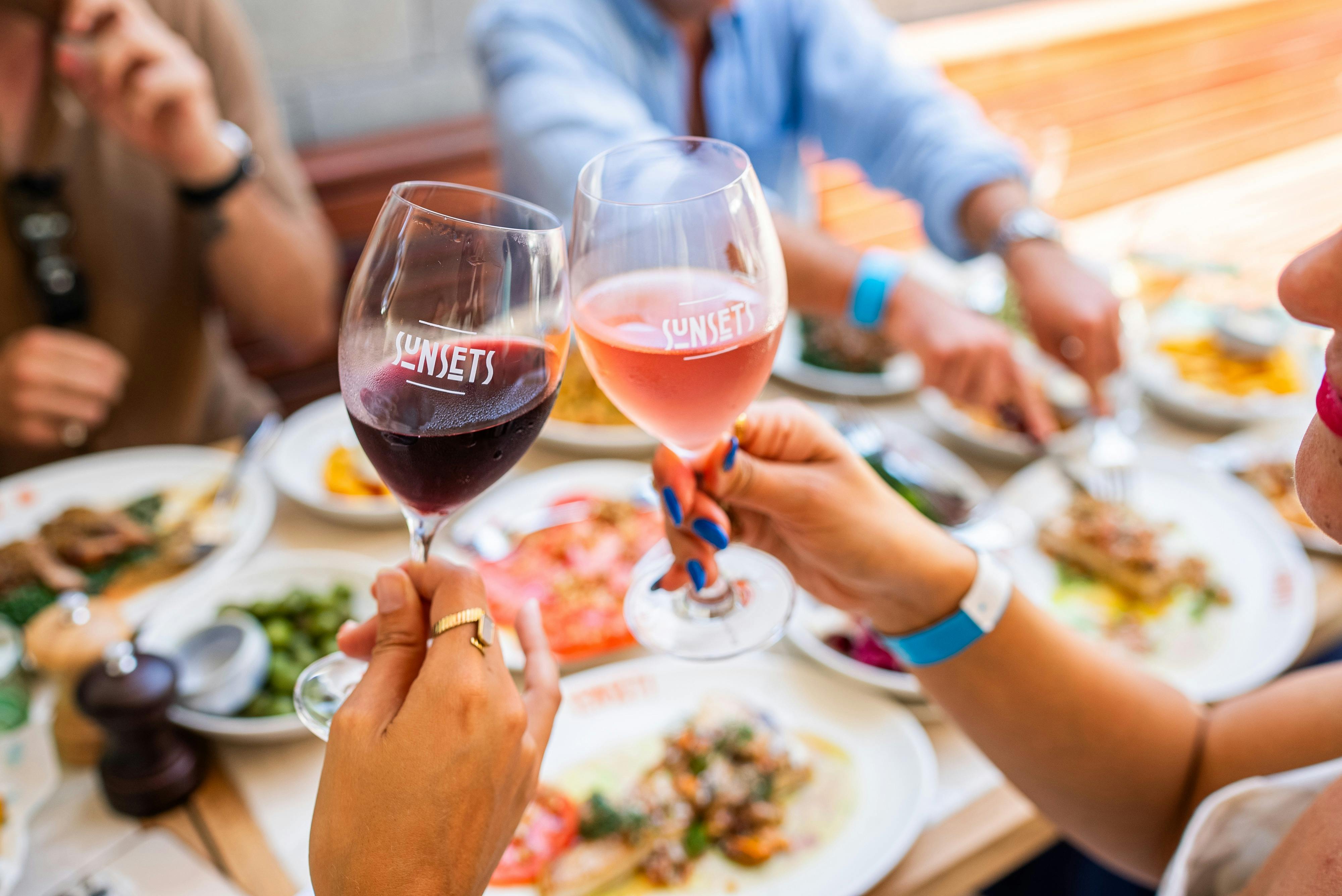 2 Wine Glasses Cheersing at Sunsets Bar & Dining