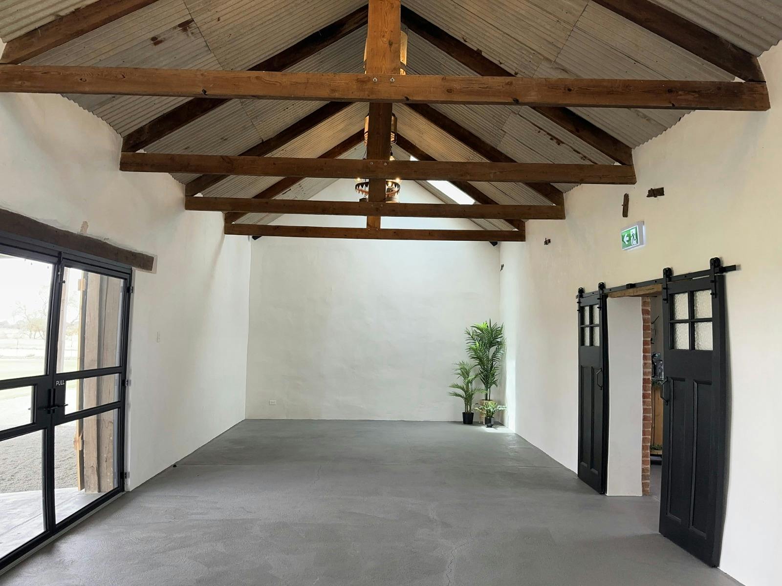 Interior of barn with limestone walls, exposed beams, corrugated ceiling & custom lighting.