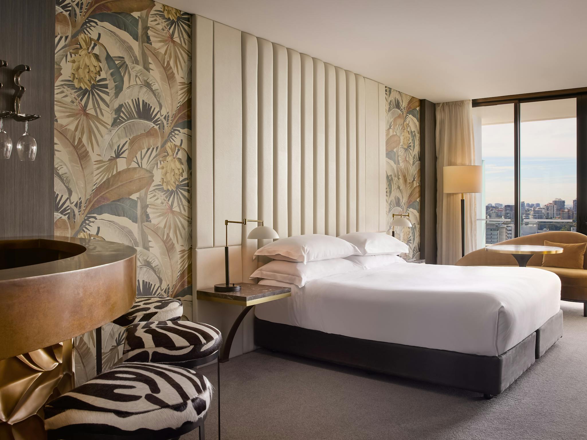 Luxury hotel room with botanical wallpaper, king bed and lounge seating overlooking the city Luxury hotel room with botanical wallpaper, king bed and lounge seating overlooking the city