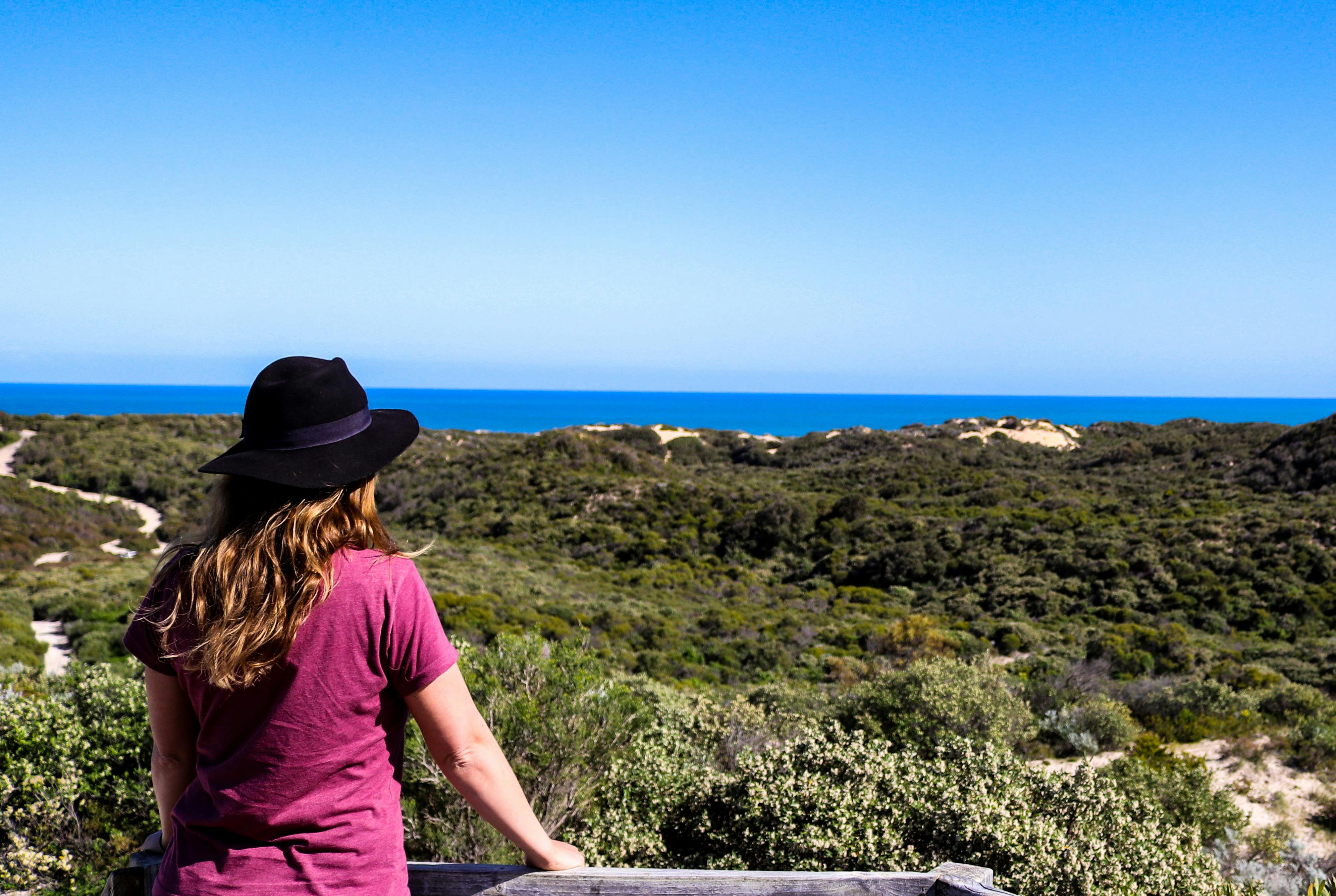 A woman in black hat looking out over a natural viewpoint