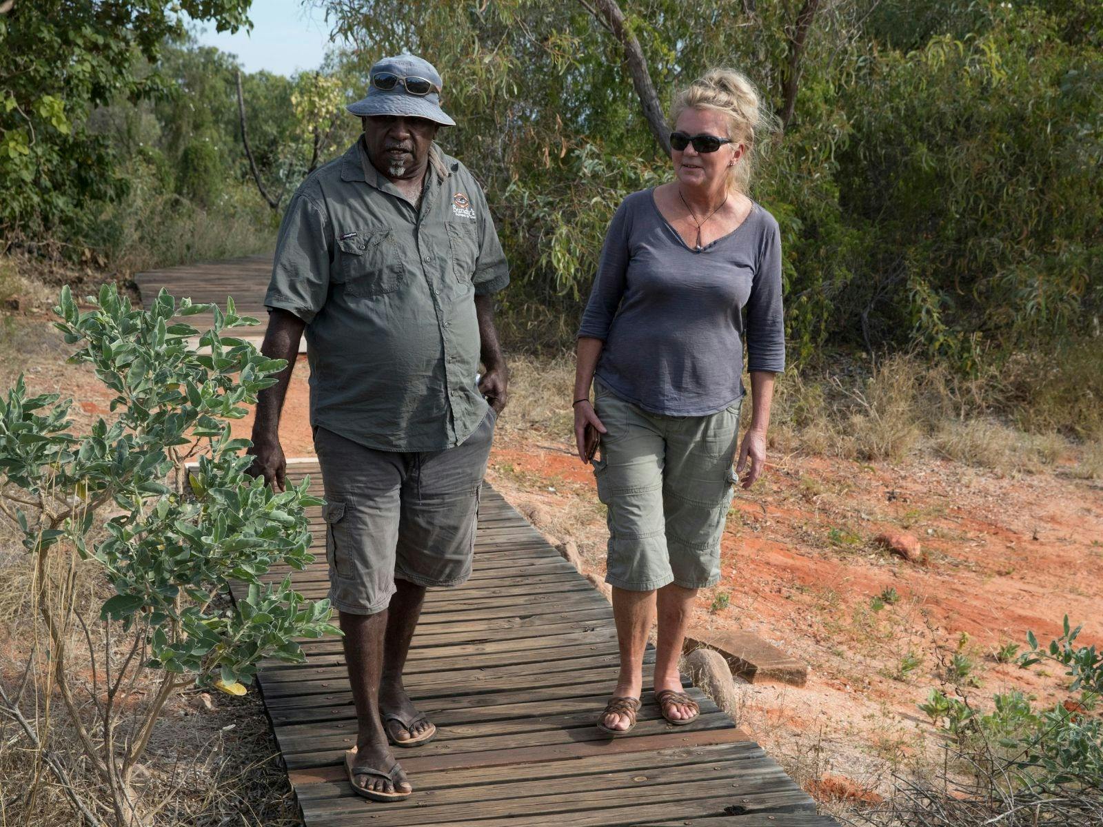 Bundy walking with tourist on wooden walkway through the bush.