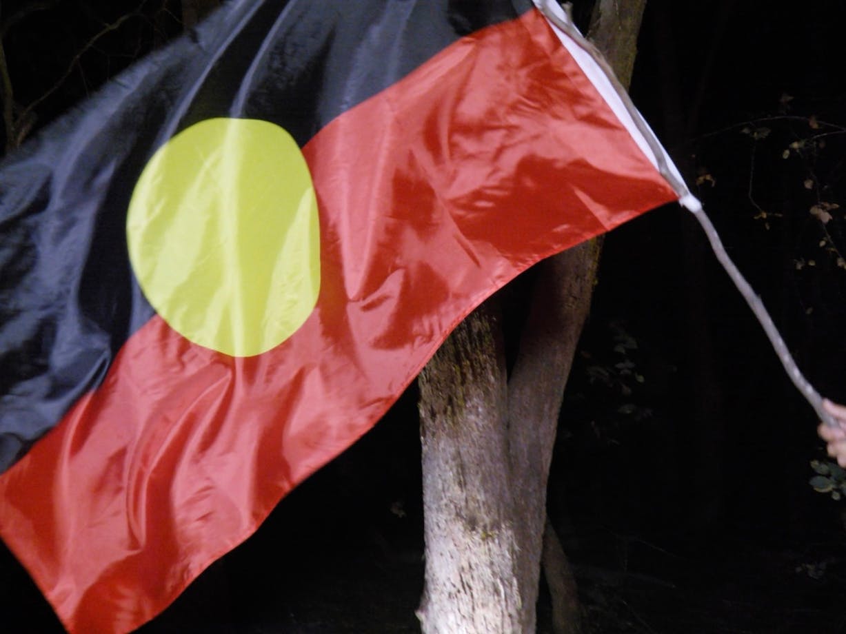 First Nations Flag on a stick, being waved in the darkness
