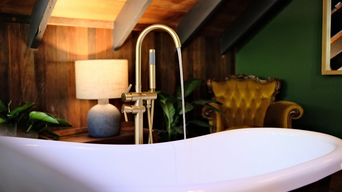 Bathroom featuring freestanding clawfoot bath, romantic lamplight and gold vintage couch