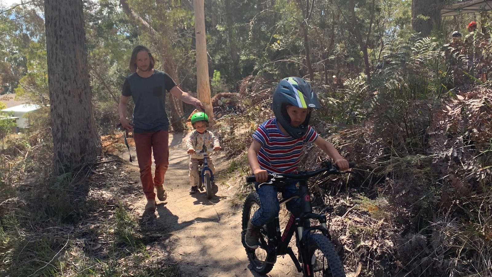 A local Dad walks with his two sons riding their bikes.