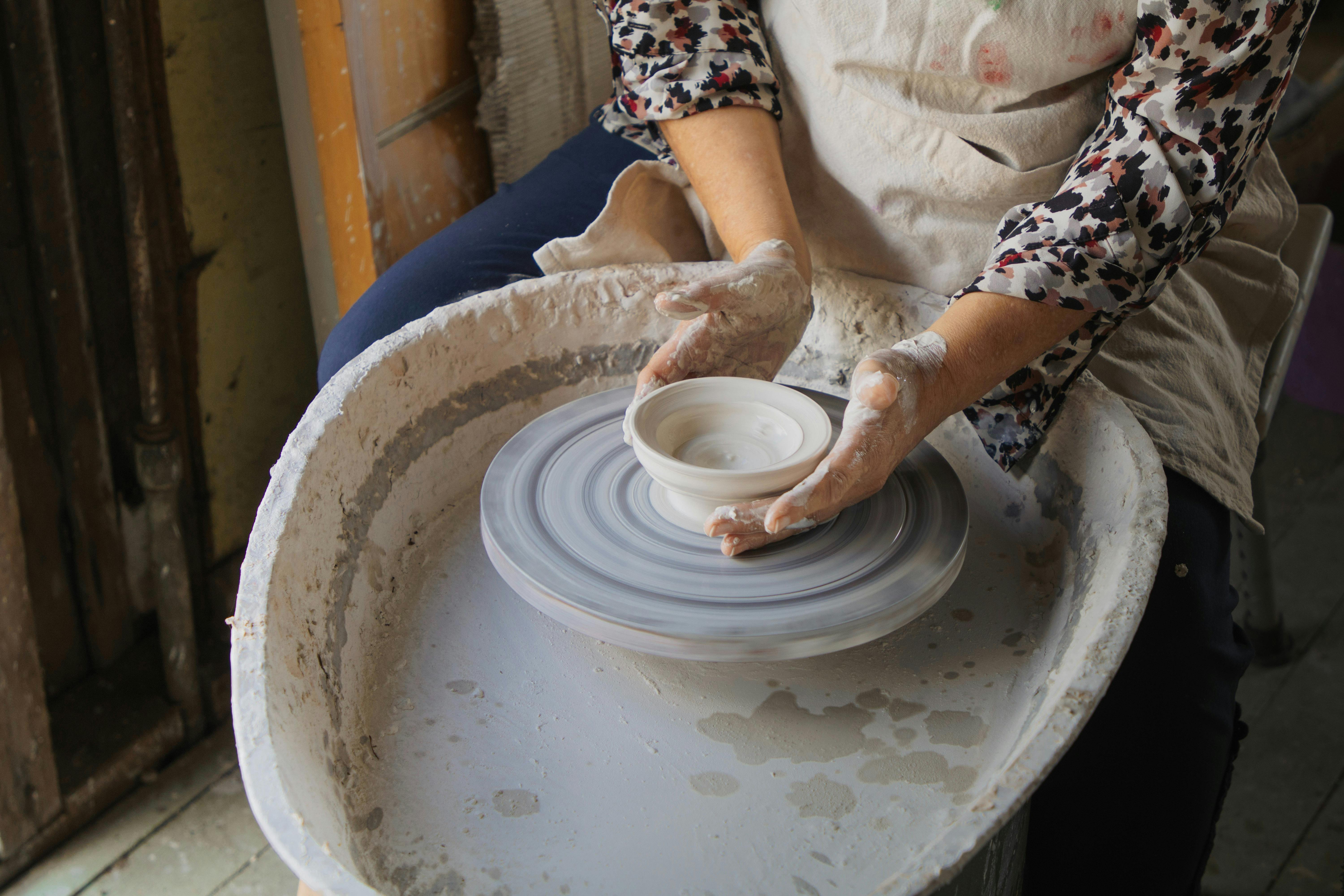 an image of hands using a pottery wheel to create a small bowl
