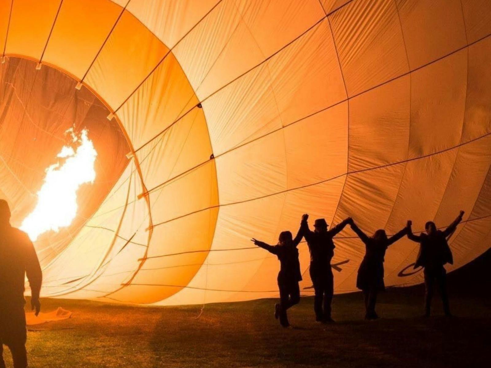 Passengers posing in front of a hot air balloon as it is prepared for lift-off