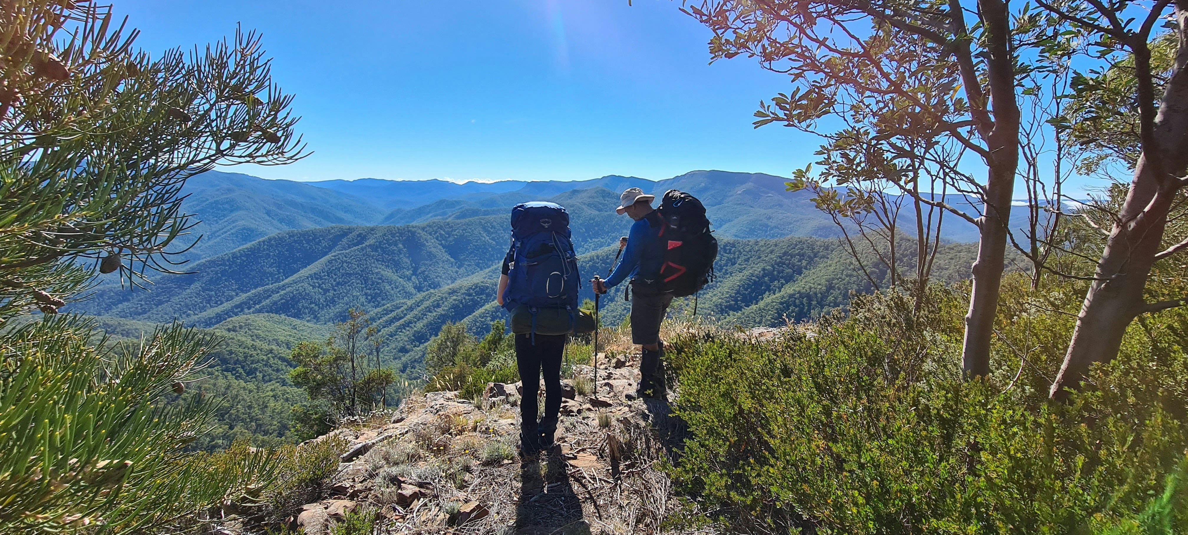 A couple of hikers soaking up mountain views from the ridge of Eagles Peaks.