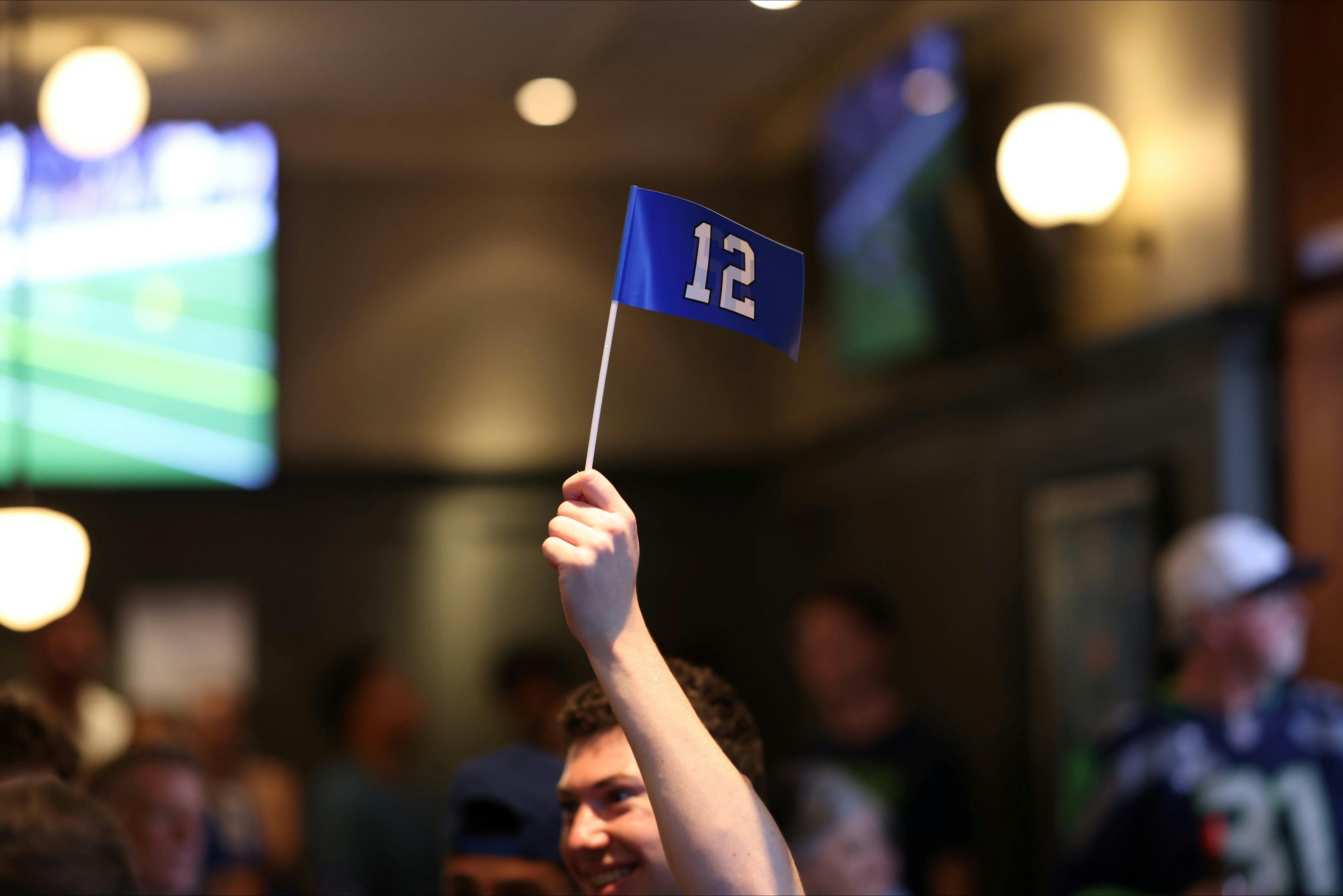 a person holding a blue flag displaying a white 12