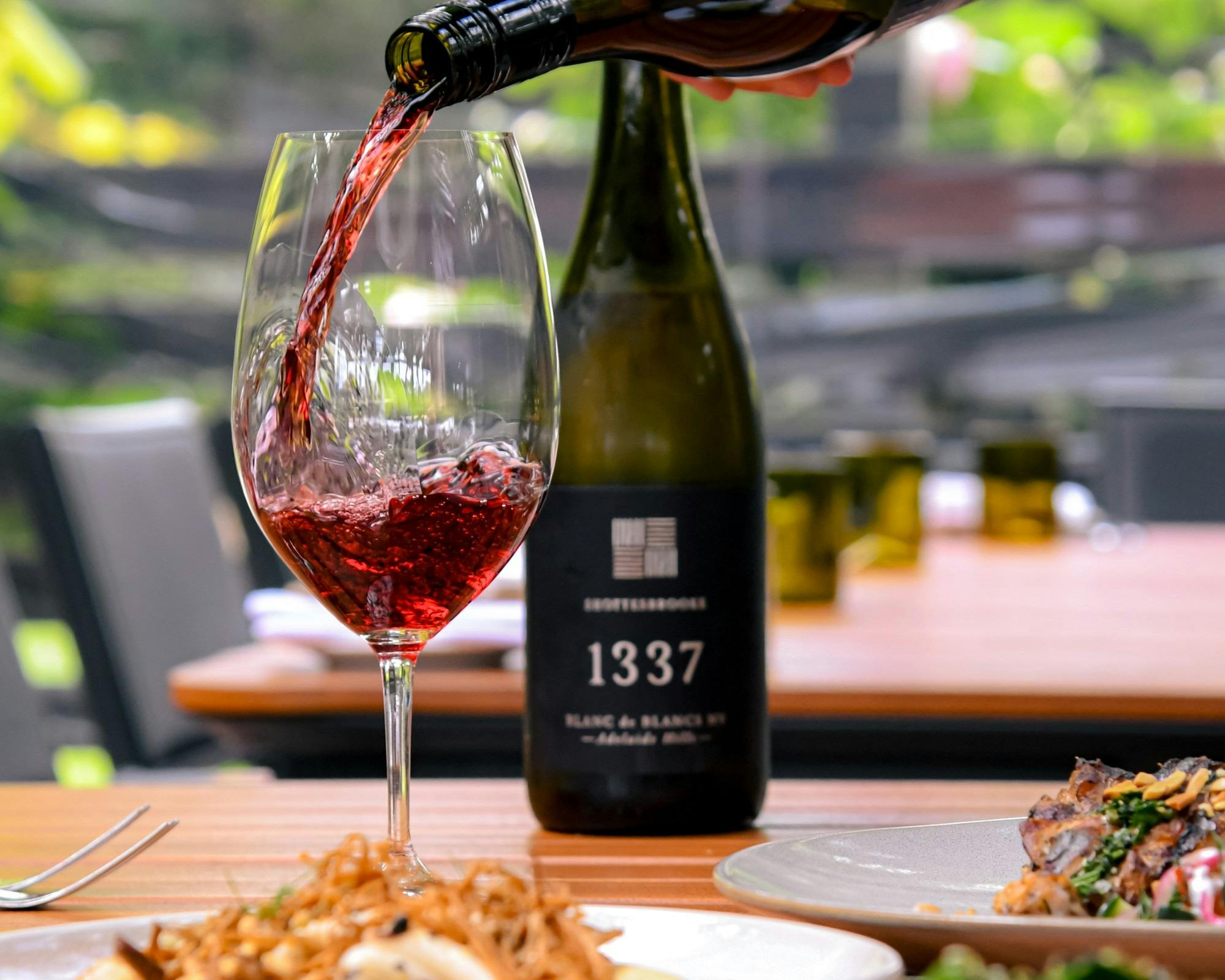 Red wine being poured into glass with bottle in background