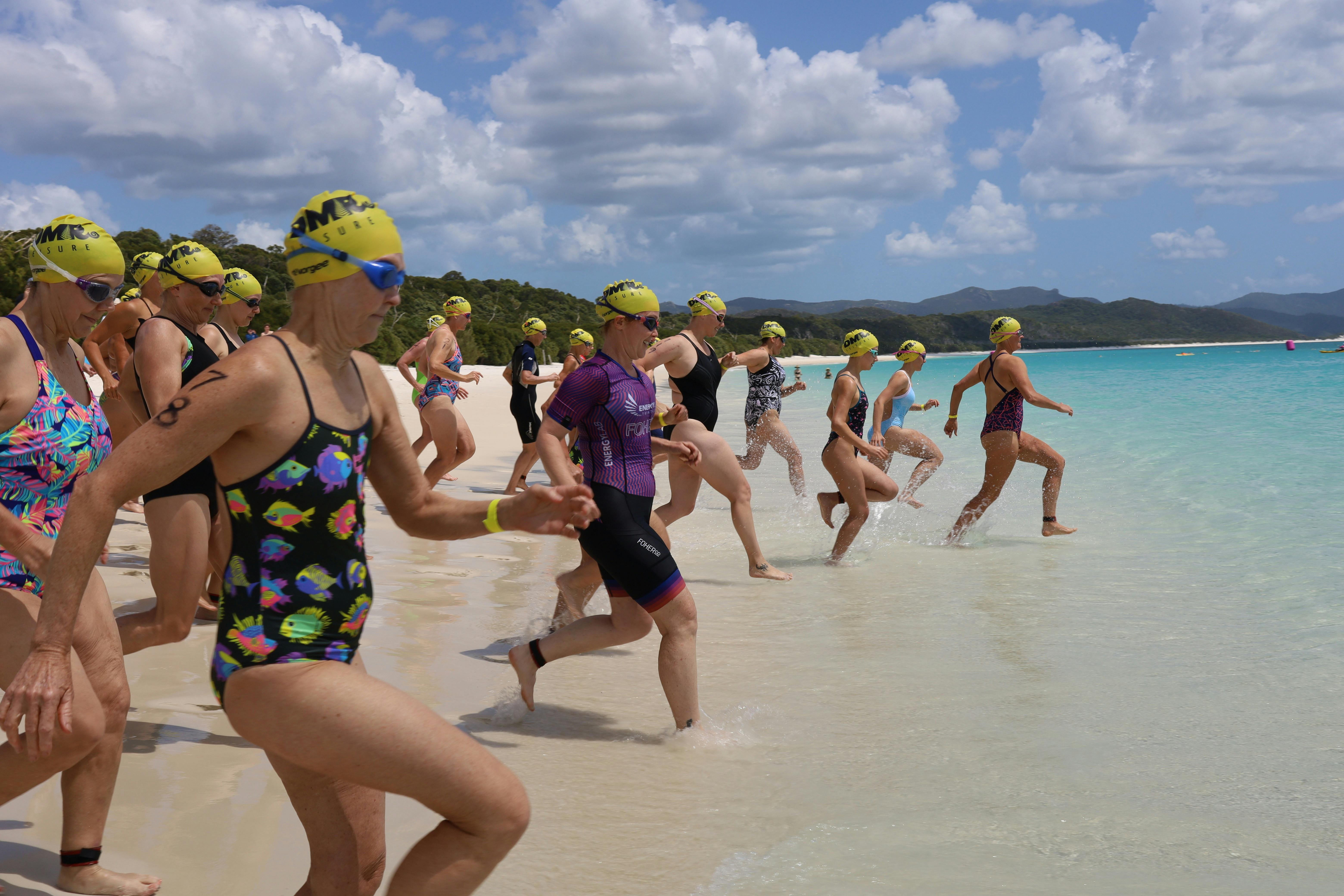 start of race for female swimmers running into the water to begin race