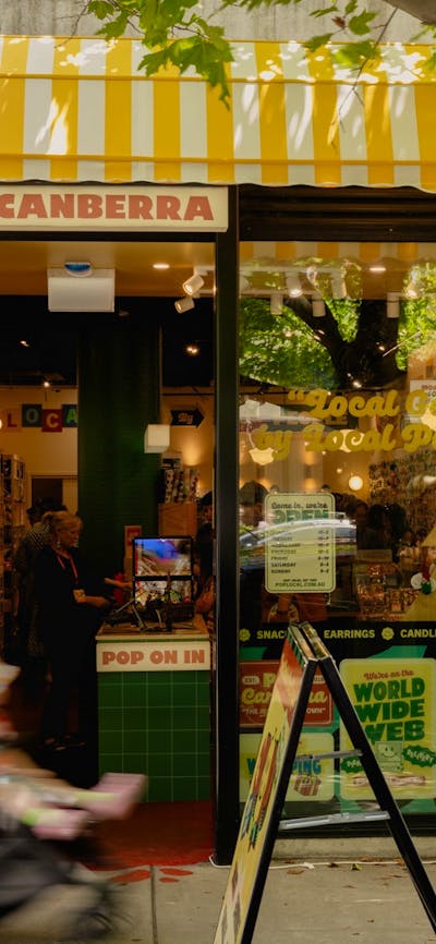 The exterior of POP Canberra, featuring its bright yellow awning, inviting signage, and good vibes.