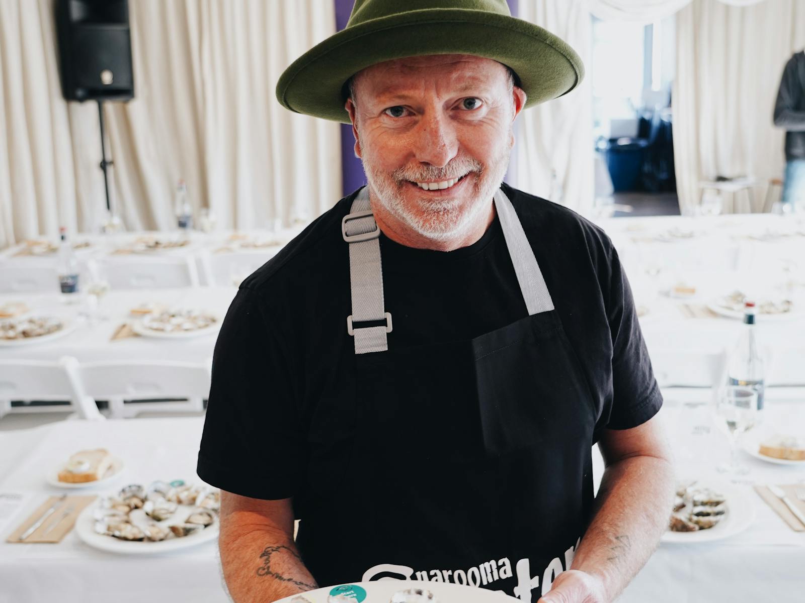 A man holds a plate of shucked oysters representing 4 estuaries and three species. It is a tasting