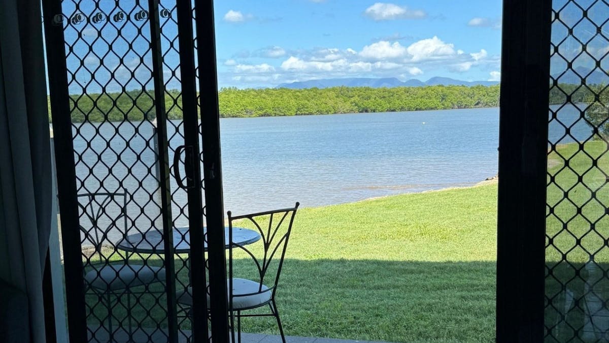 Grass and water views from double sliding door, with table and chairs