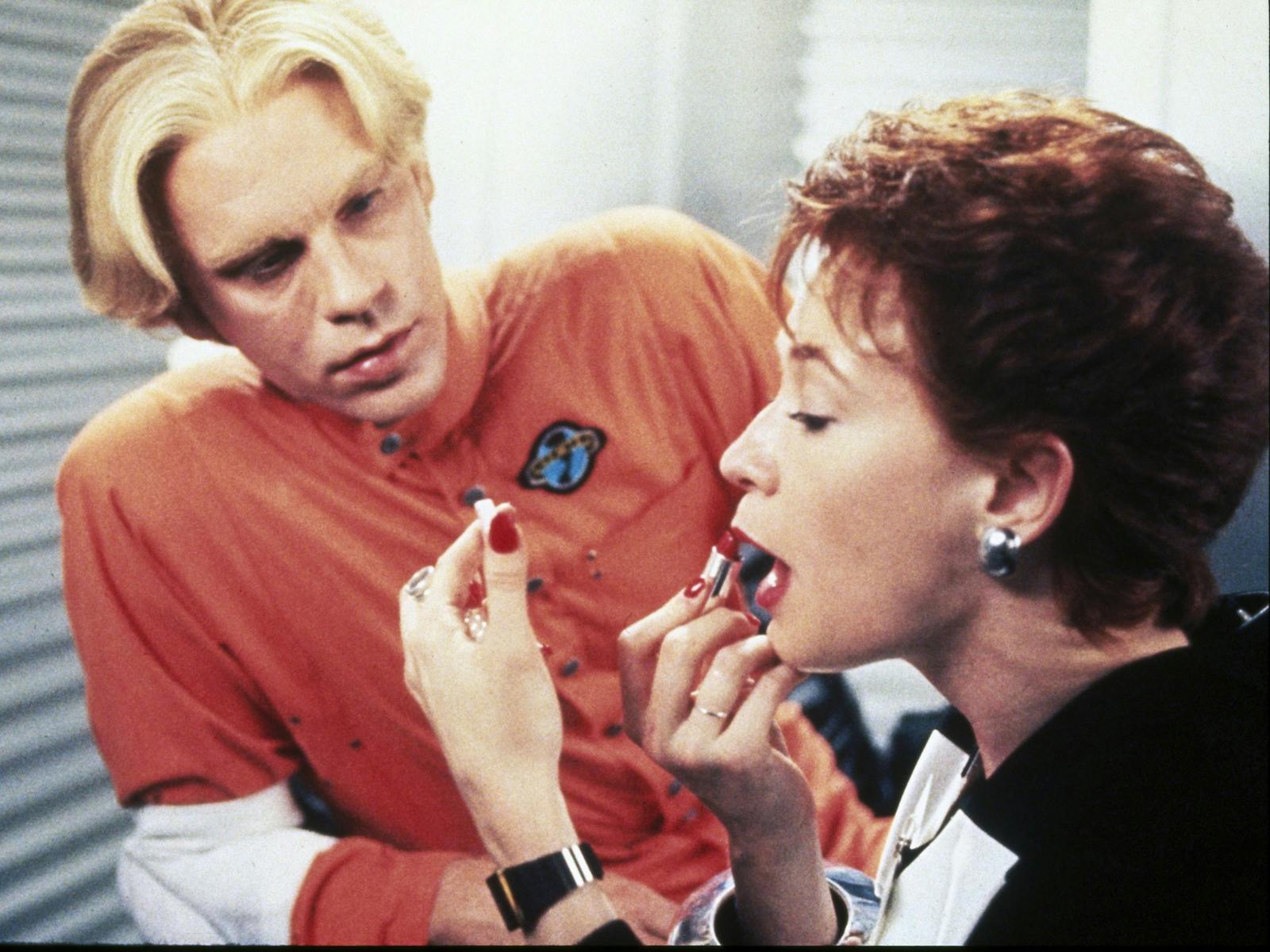 man watching a woman apply lipstick