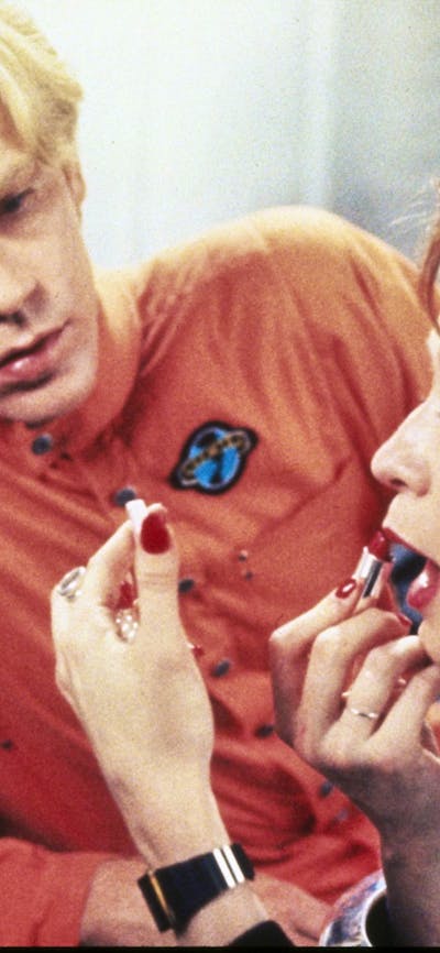 man watching a woman apply lipstick