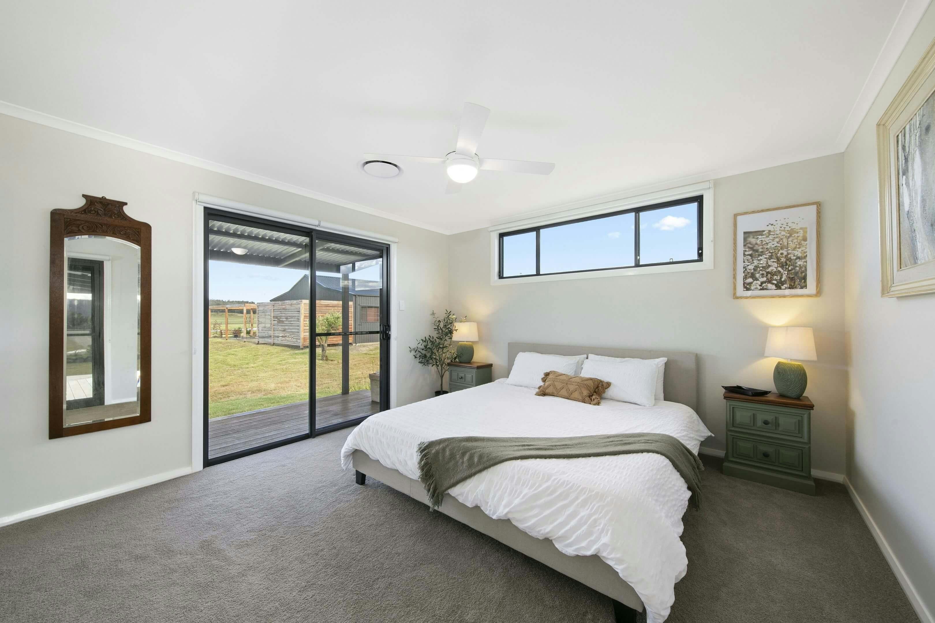 bedroom with a large bed, two green bedside tables with lamps, a sliding glass door to the patio