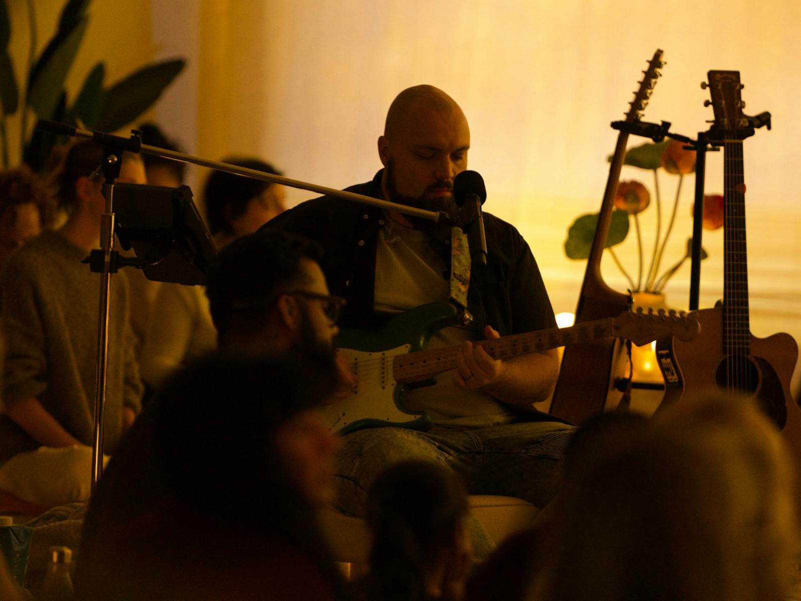 Man seated playing guitar in a crowd