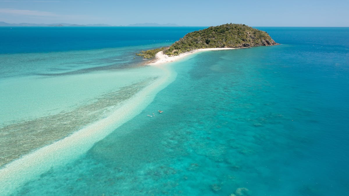 View to a small hilly island with a long sandy cay at low ocean tide