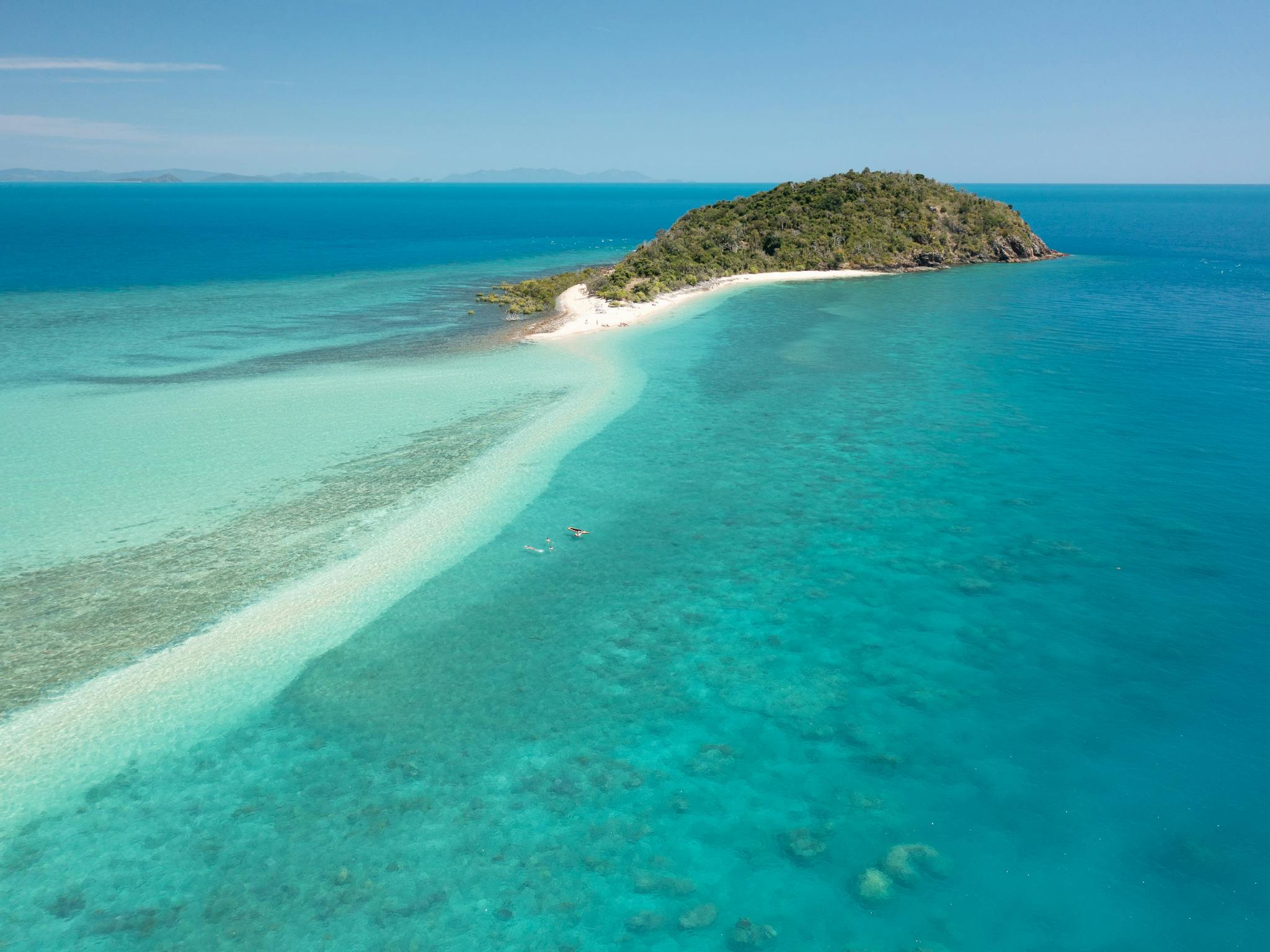 View to a small hilly island with a long sandy cay at low ocean tide View to a small hilly island with a long sandy cay at low ocean tide
