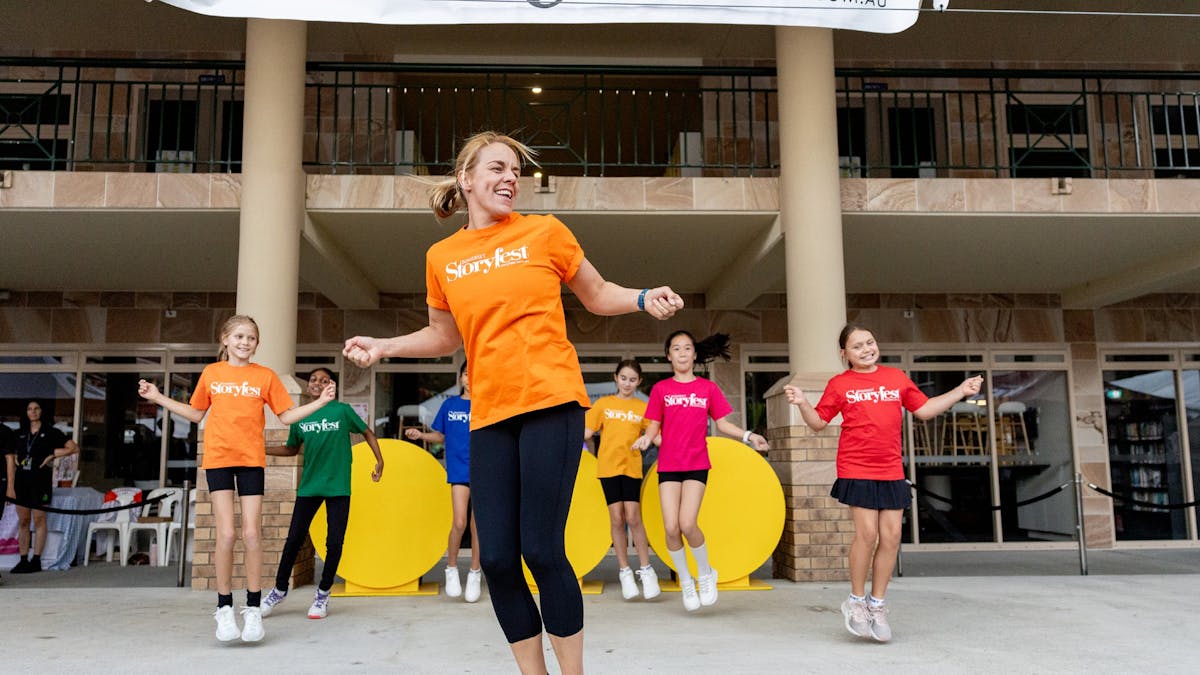 Group of children and an instructor performing a dance routine at a Storyfest event