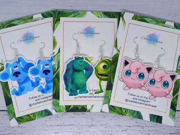 Three pairs of colourful picture earrings featuring cartoon-style designs Three pairs of colourful picture earrings featuring cartoon-style designs