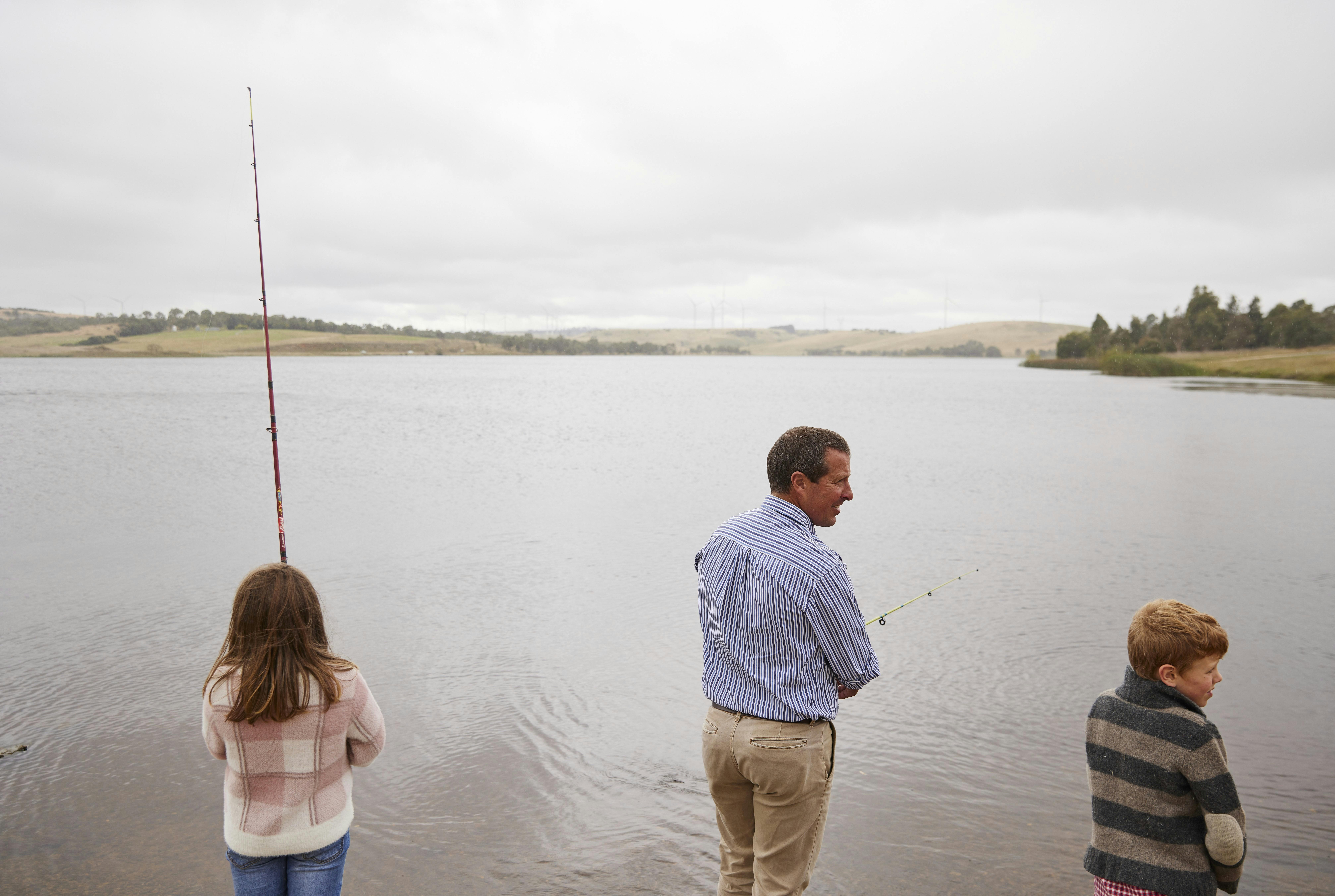 Young girl, adult male and boy standing on the edge of Pejar Dam