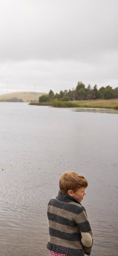 Young girl, adult male and boy standing on the edge of Pejar Dam