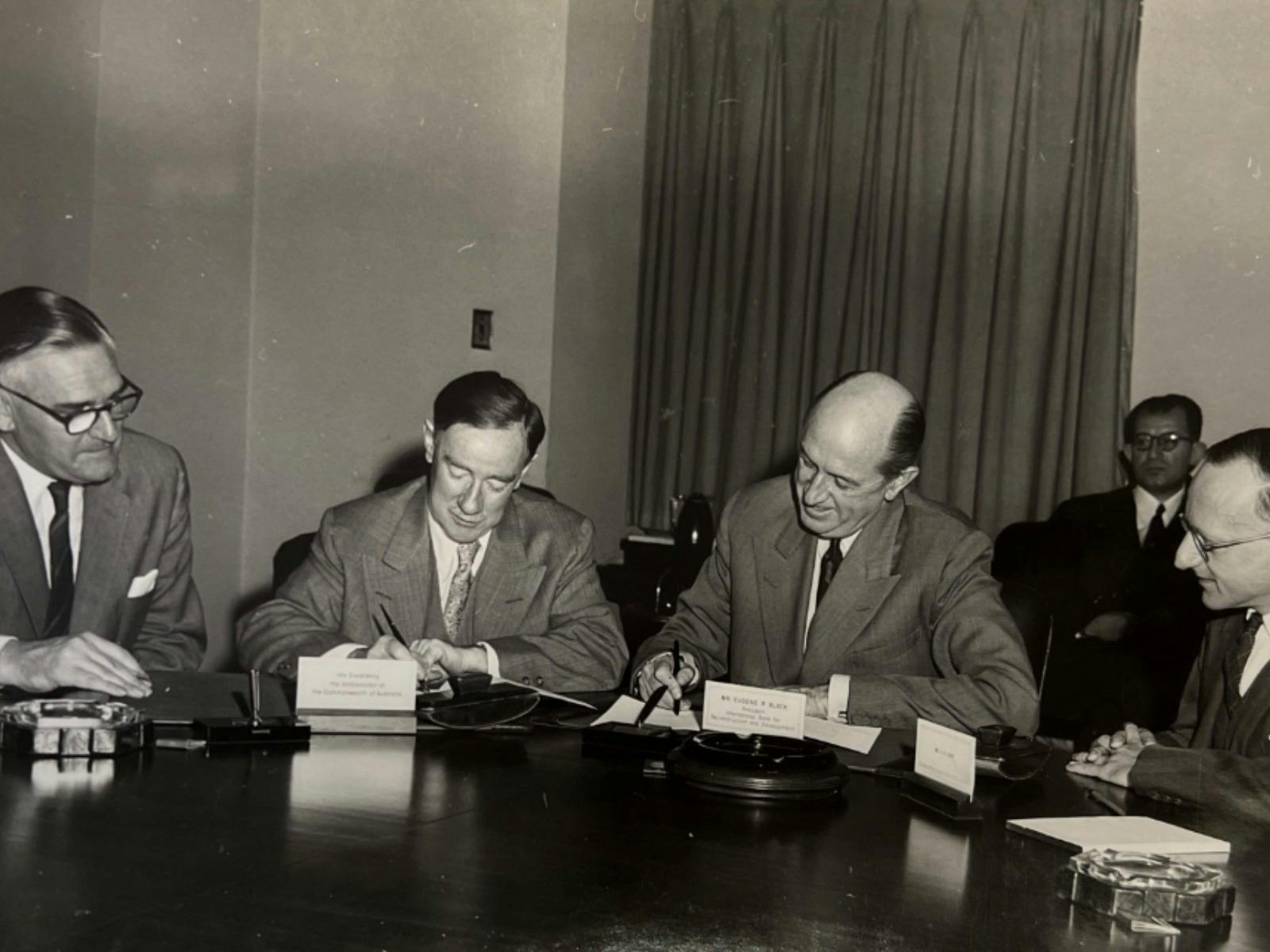 A sepia photograph of four gentlemen writing.
