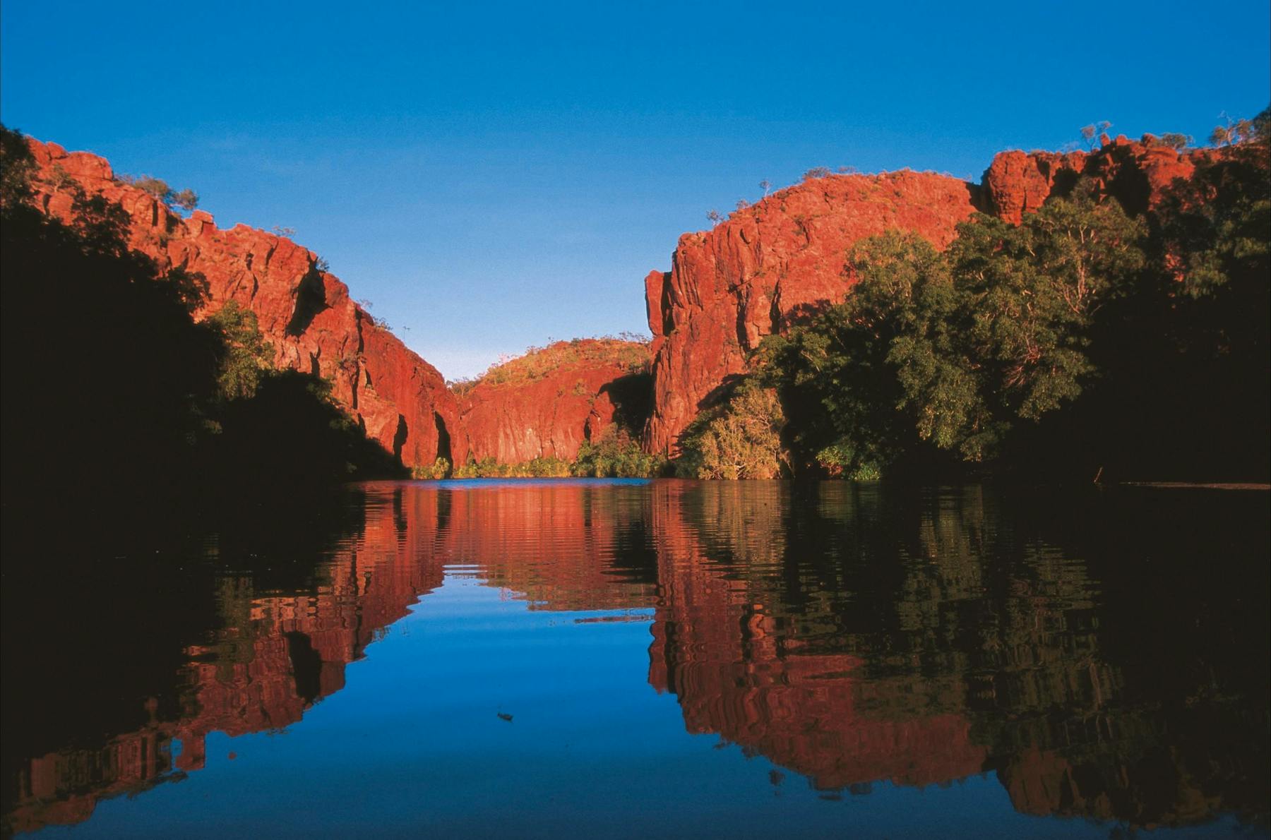 Red sandstone cliffs reflected on blue waters of Lawn Hill Creek.