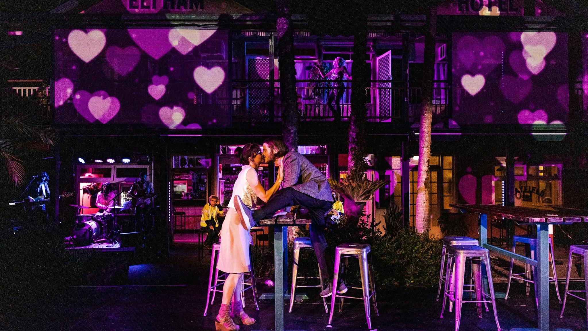 A couple embrace against the backdrop of the Elthem Hotel