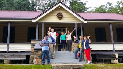 Six seniors and tour guide on steps of caves house 1901