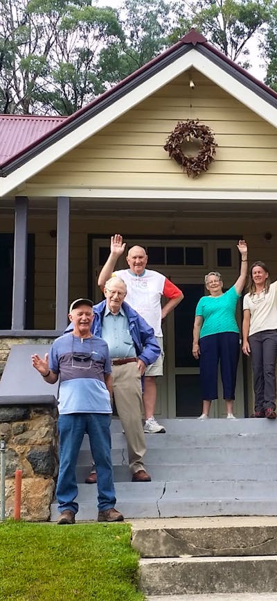 Six seniors and tour guide on steps of caves house 1901