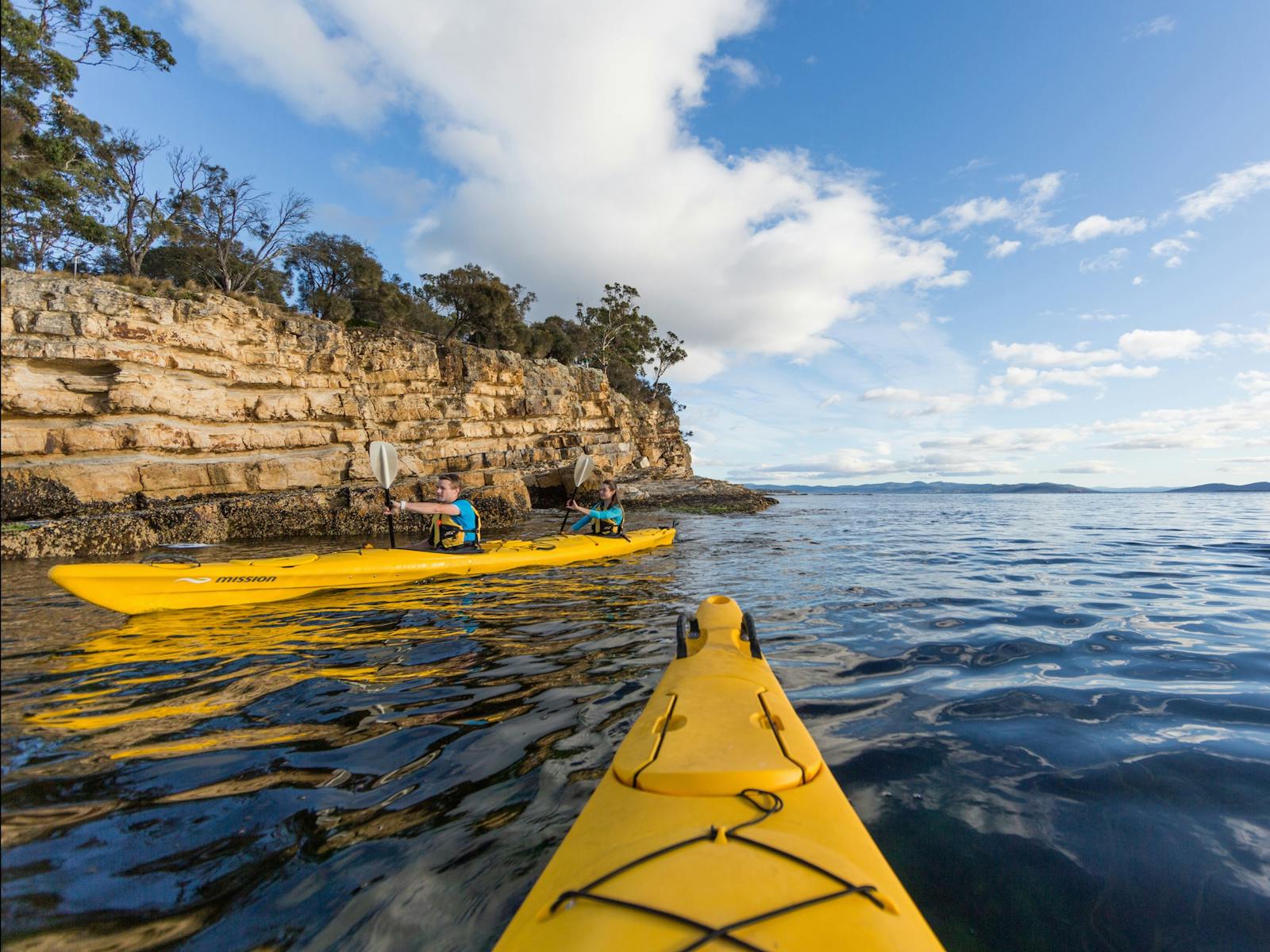 Kayakers paddling beside cliffs on Hobart's Derwent River