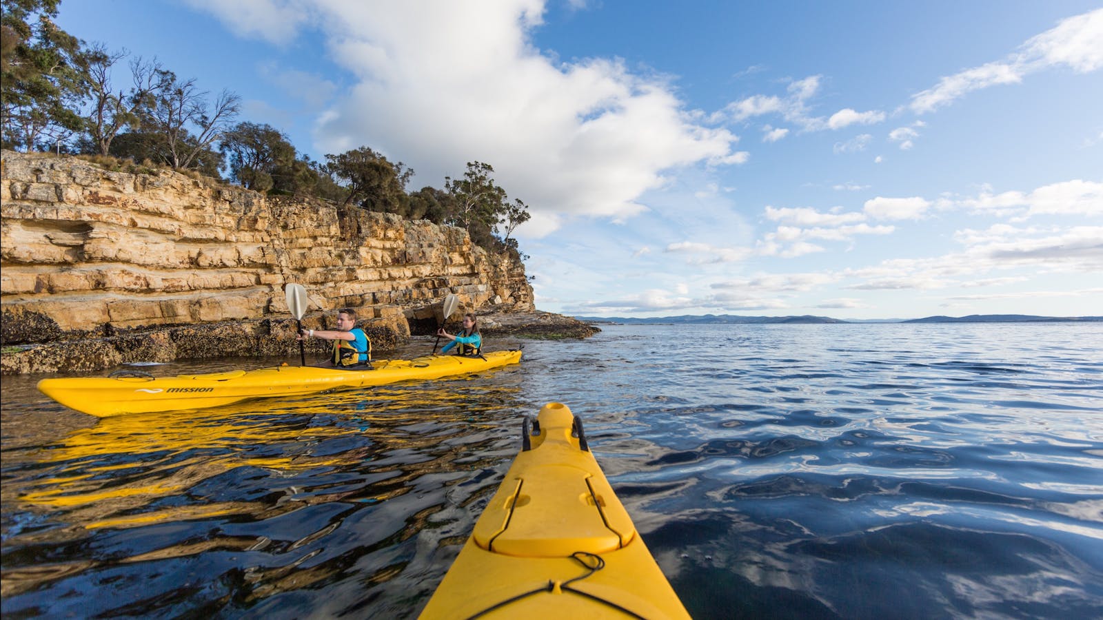 Kayakers paddling beside cliffs on Hobart's Derwent River