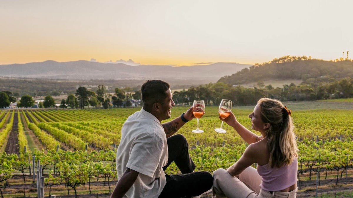 A couple enjoys a glass of wine at Dear Vincent Winery overlooking the vineyard