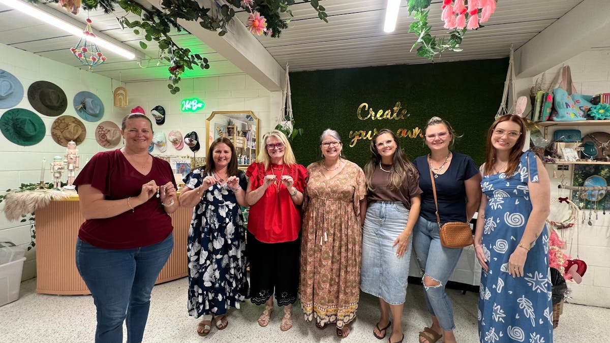 Happy artists paint ther artwork in a paint and sip experience under a beautiful indoor tree studio