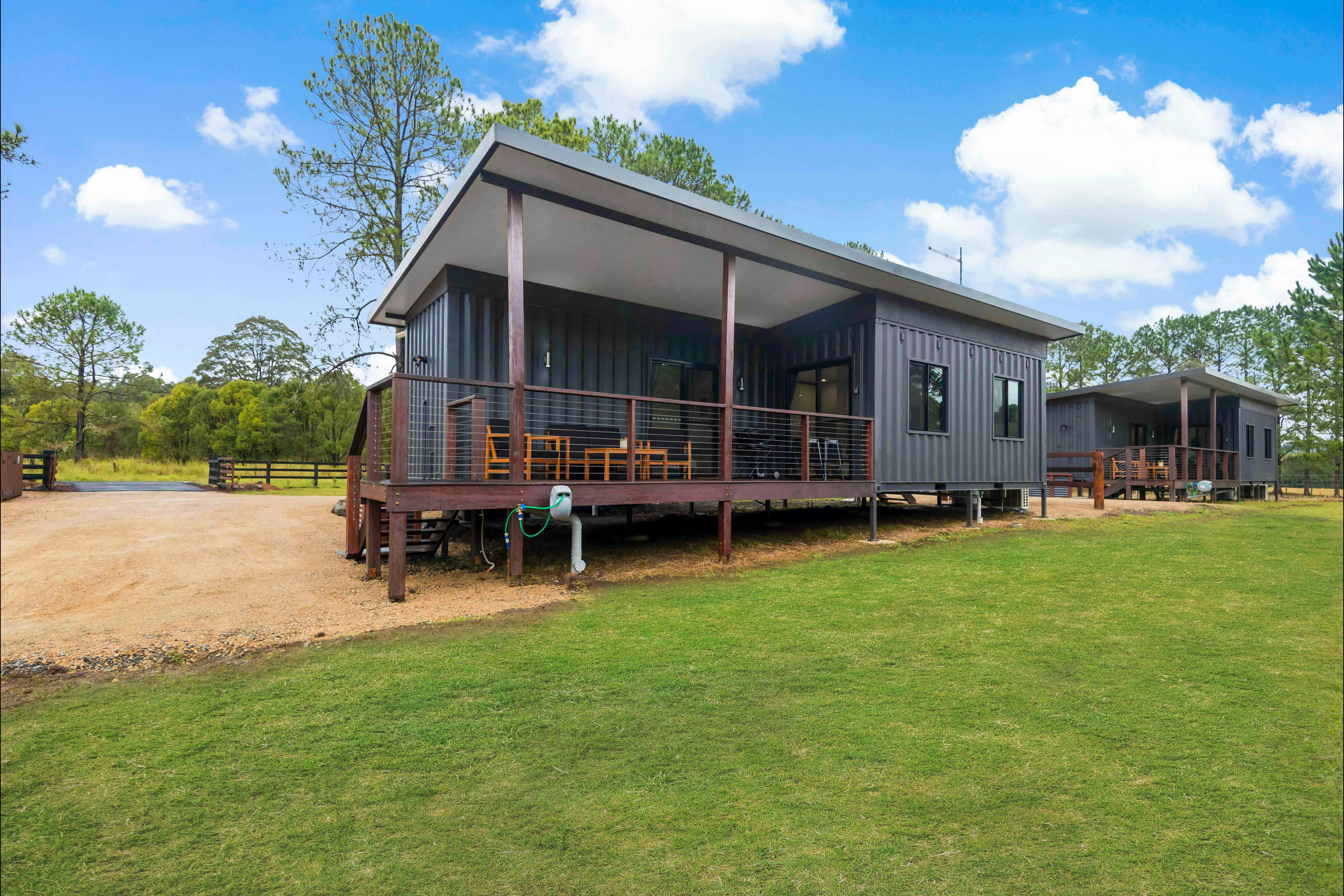 External shot of Wollumbin cottage showing exterior and deck. Parking spot is beside the cottage