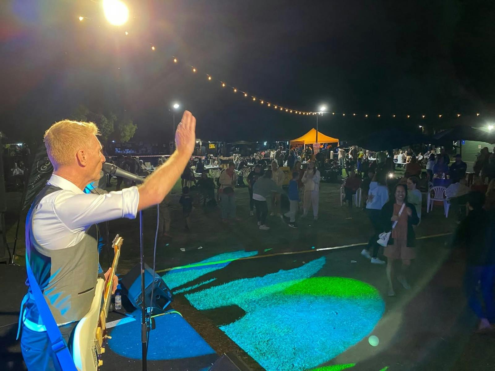a singer with a microphone and a guitar facing a crowd of people