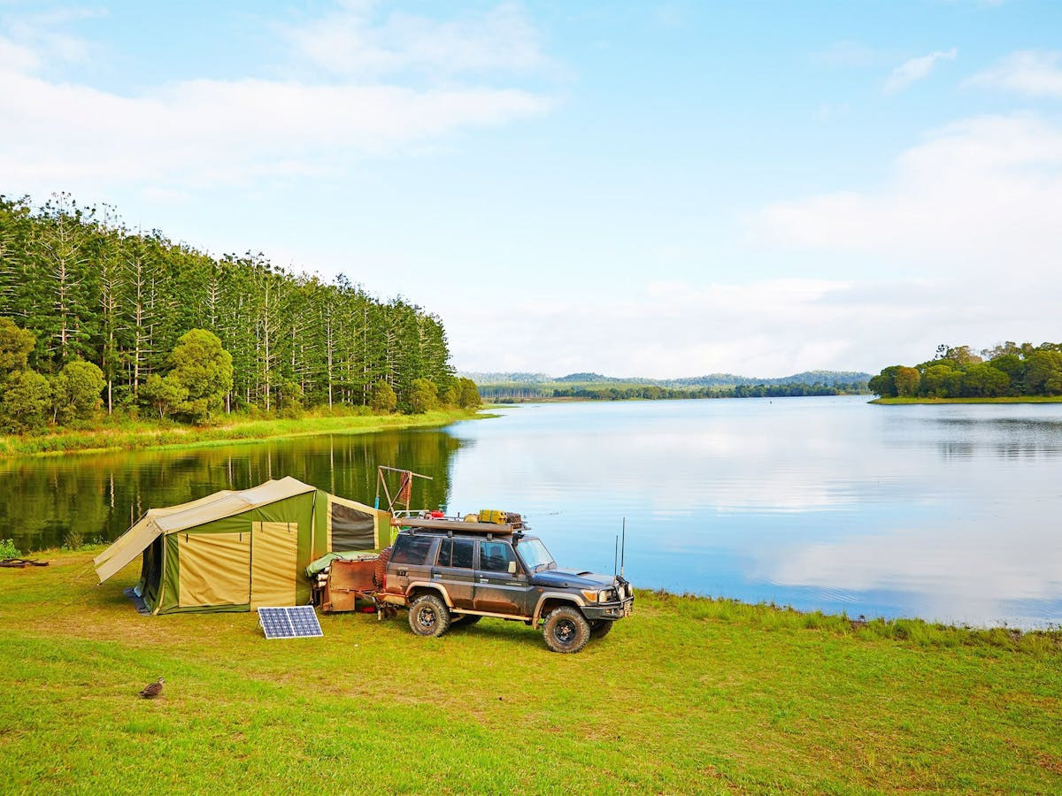 Four-wheel-drive vehicle and tent set up on the banks of Lake Tinaroo