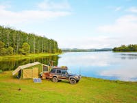 Four-wheel-drive vehicle and tent set up on the banks of Lake Tinaroo