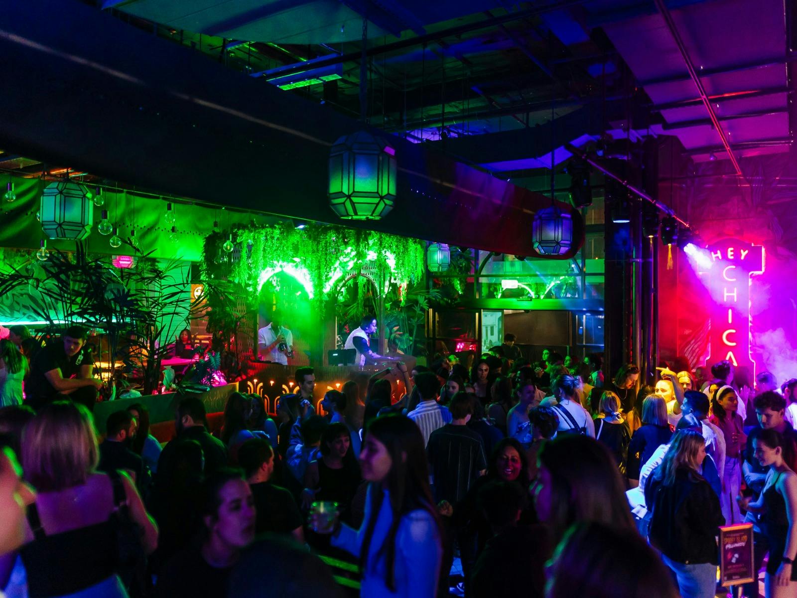 Dance floor with people dancing and neon lights shining in green and pink