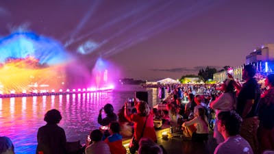 People gather aroudn a light display on Lake Burley Griffin