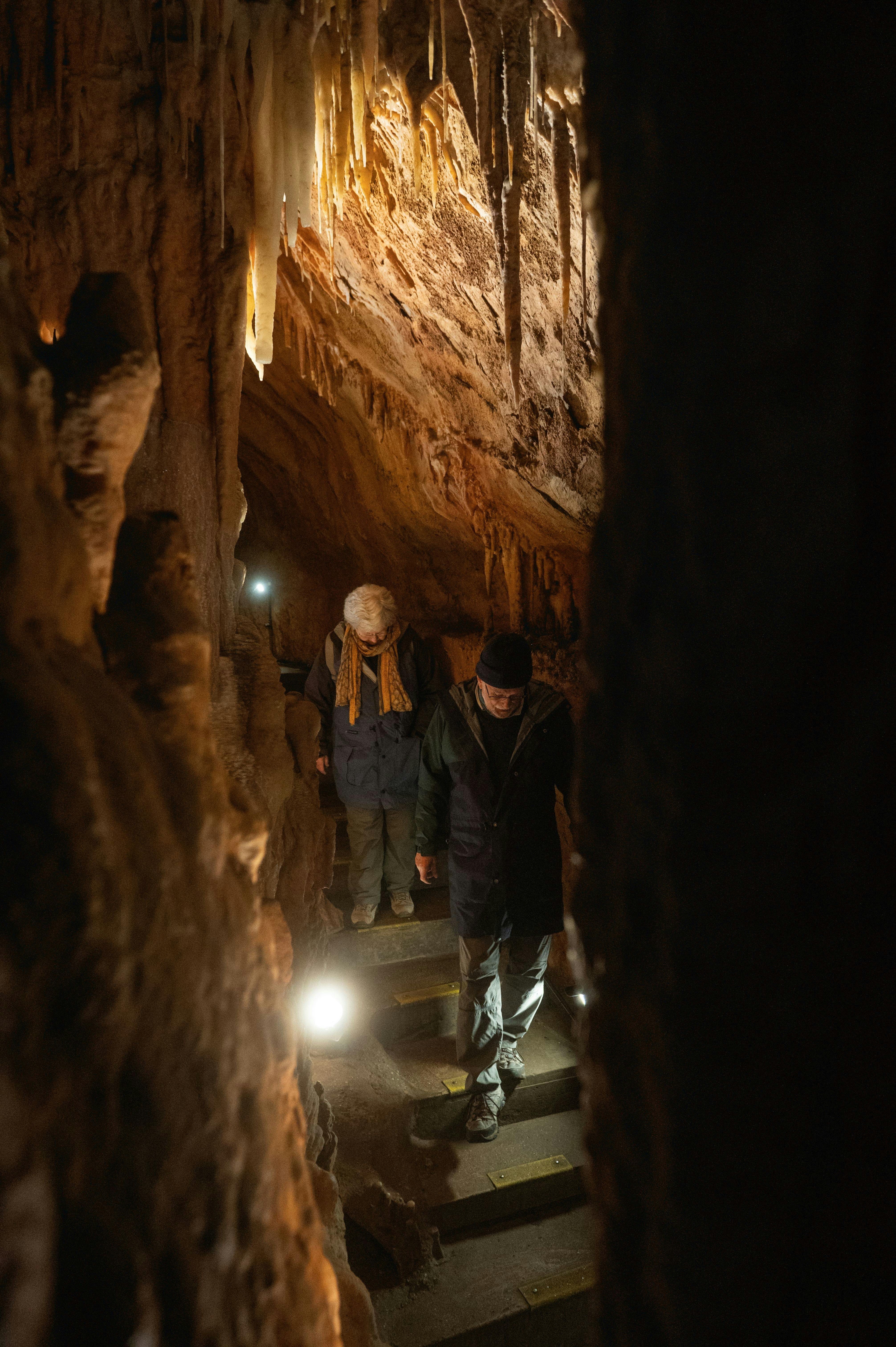 two people walking down a flight of steps surrounded by cave walls on either side