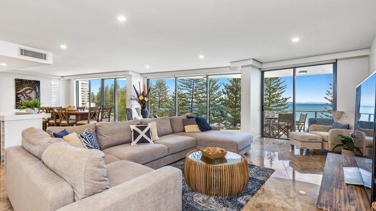 Cozy lounge with warm tones, grey corner sofa, marble tiles, and beautiful ocean views Cozy lounge with warm tones, grey corner sofa, marble tiles, and beautiful ocean views