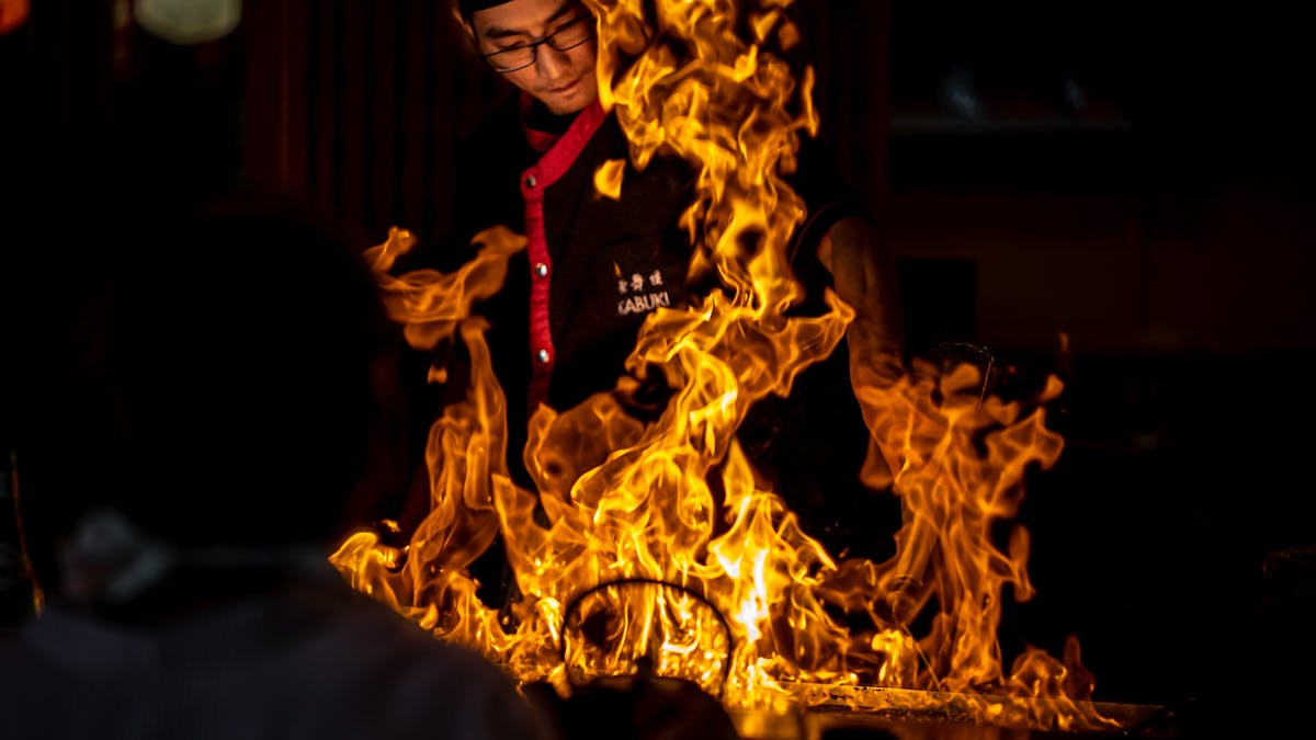Teppanyaki chef behind a flame on a grill